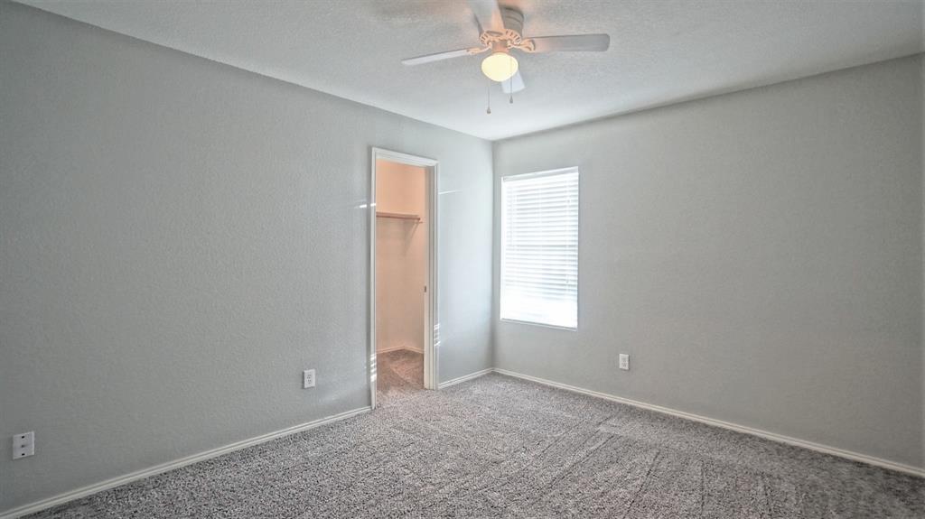 12005 Arbor Lake Road Rhome, TX 76078 - Photo 15 of 22 Unfurnished bedroom featuring a walk in closet, carpet flooring, ceiling fan, a textured ceiling, and a textured wall