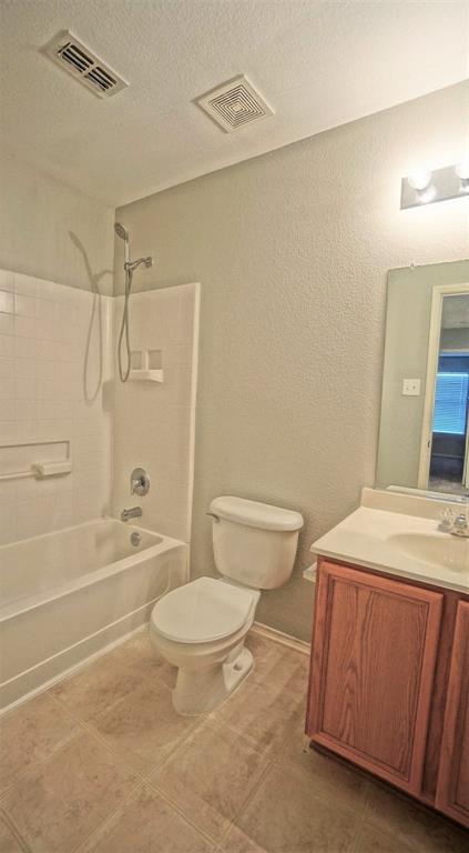 12005 Arbor Lake Road Rhome, TX 76078 - Photo 18 of 22 Bathroom with a textured ceiling, shower combination, vanity, a textured wall, and tile patterned flooring