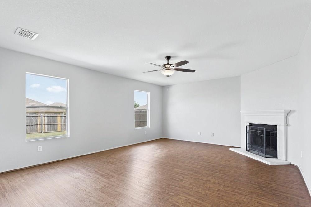 12005 Arbor Lake Road Rhome, TX 76078 - Photo 6 of 22 Unfurnished living room featuring wood finished floors, ceiling fan, and a fireplace with raised hearth