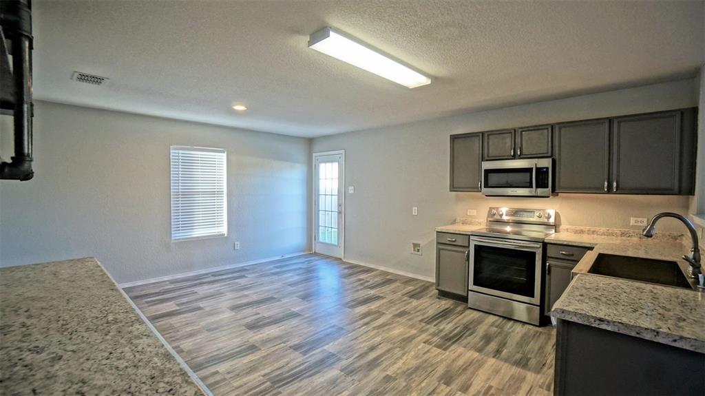 12005 Arbor Lake Road Rhome, TX 76078 - Photo 8 of 22 Kitchen with a textured ceiling, appliances with stainless steel finishes, and wood finished floors