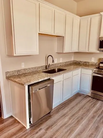 a kitchen with granite countertop a sink dishwasher a stove and a microwave oven with cabinets