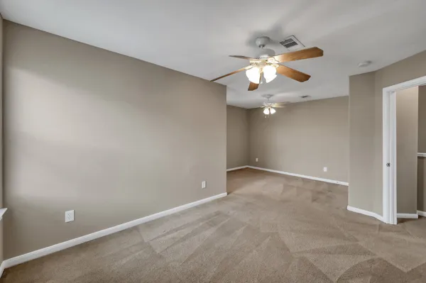 a view of an empty room and chandelier fan