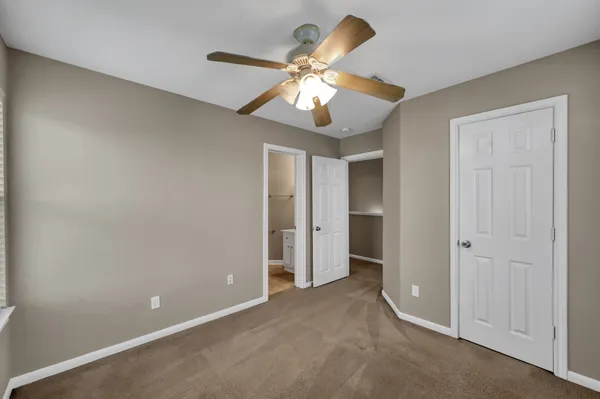 a view of an empty room and chandelier fan