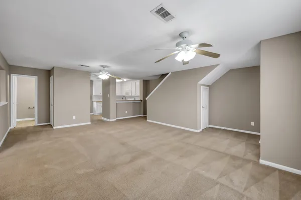 a view of an empty room and chandelier fan