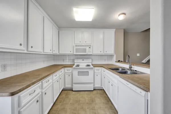a kitchen with granite countertop white cabinets and white appliances