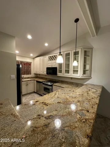 a kitchen with stainless steel appliances granite countertop a sink a stove and a refrigerator