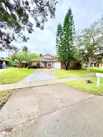 a view of a house with a big yard and large trees