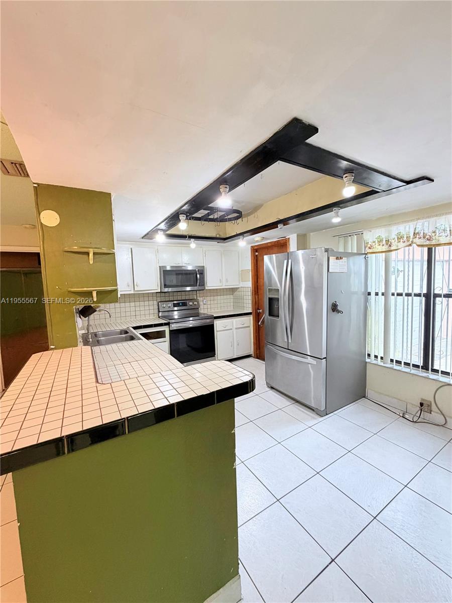 11334 Southwest 152nd Terrace Miami, FL 33157 - Photo 8 of 20 a kitchen with stainless steel appliances kitchen island a sink refrigerator and cabinets