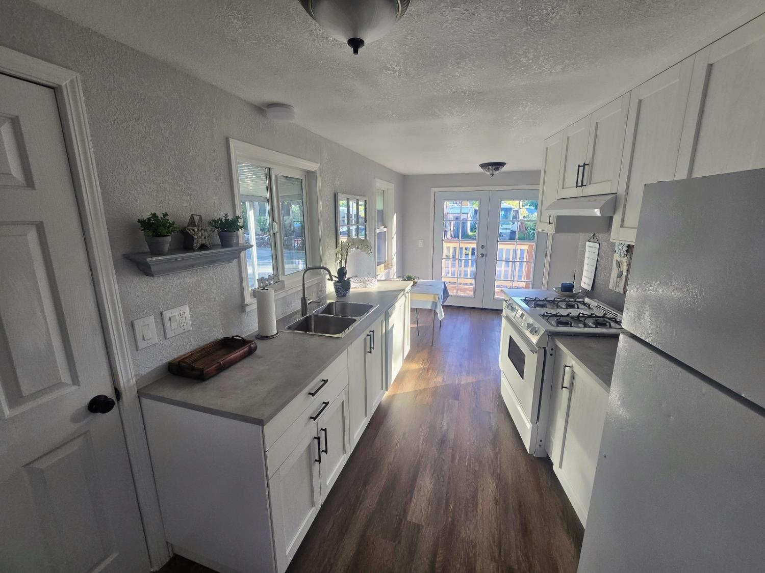 450 Gladycon Road, Unit 3 Colfax, CA 95713 - Photo 15 of 27 a kitchen with granite countertop a refrigerator a sink dishwasher stove and white countertops with wooden floor