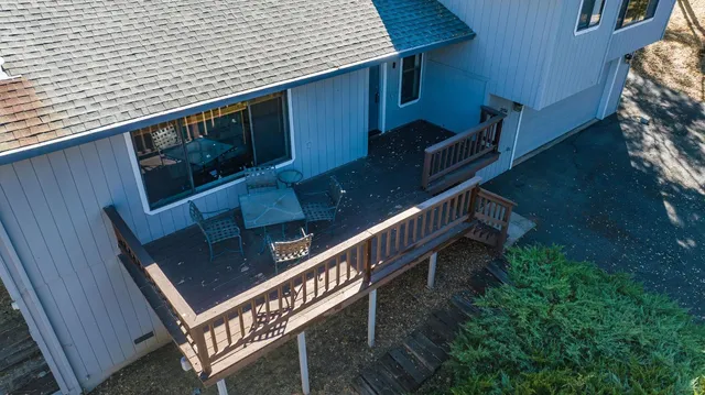 a view of a wooden house with a wooden deck and furniture