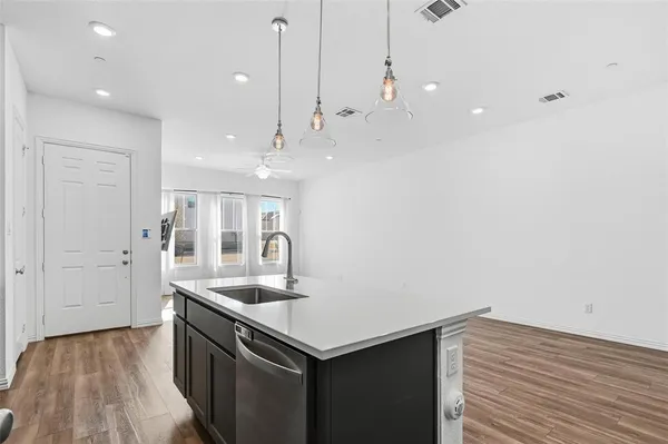 a kitchen with a sink chandelier and wooden floor