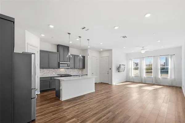 a large kitchen with stainless steel appliances kitchen island a large counter top and a wooden floors