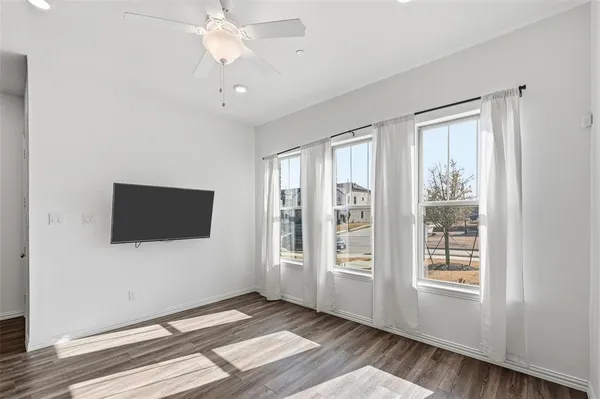 a view of an empty room with window and wooden floor