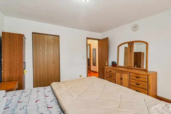 a bedroom with a bed and a dresser with mirror