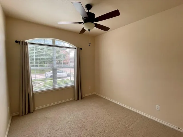 an empty room with a window and a ceiling fan