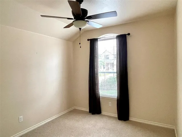 an empty room with a ceiling fan and a window