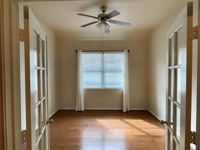 an empty room with window and a ceiling fan