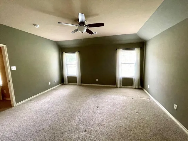 an empty room with windows and fan