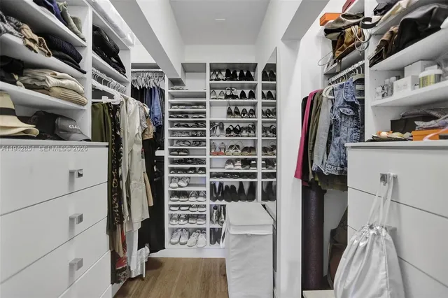 a view of walk in closet with clothes and shoes