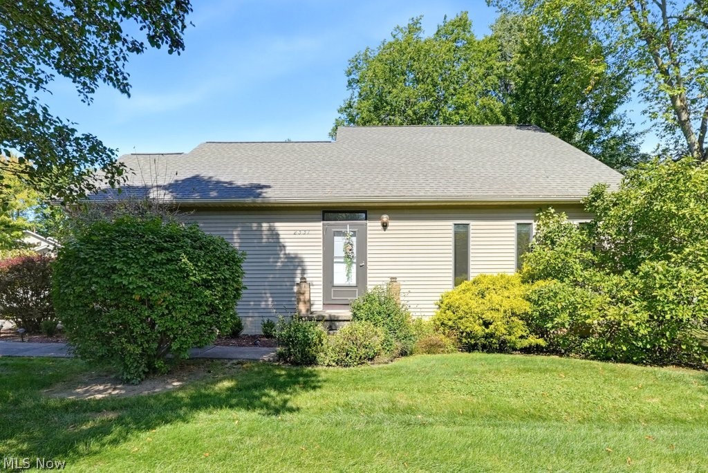 Siding exterior with a covered entry, established landscaping, and a manicured lawn