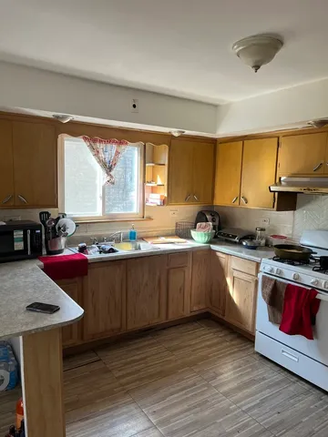 a kitchen with stainless steel appliances granite countertop wooden cabinets a stove a sink and dishwasher with wooden floor