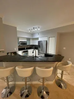 a kitchen with stainless steel appliances kitchen island granite countertop a table chairs in it and wooden floors