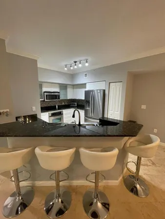 a kitchen with stainless steel appliances kitchen island granite countertop a table chairs in it and wooden floors