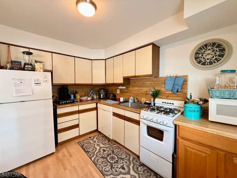 1241 Valley Road, Unit 1241 Wayne, NJ 07470 - Photo 5 of 12 a kitchen with a refrigerator a stove a microwave and cabinets