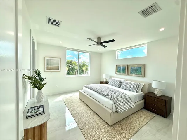 a spacious bedroom with a bed lamp and a potted plant