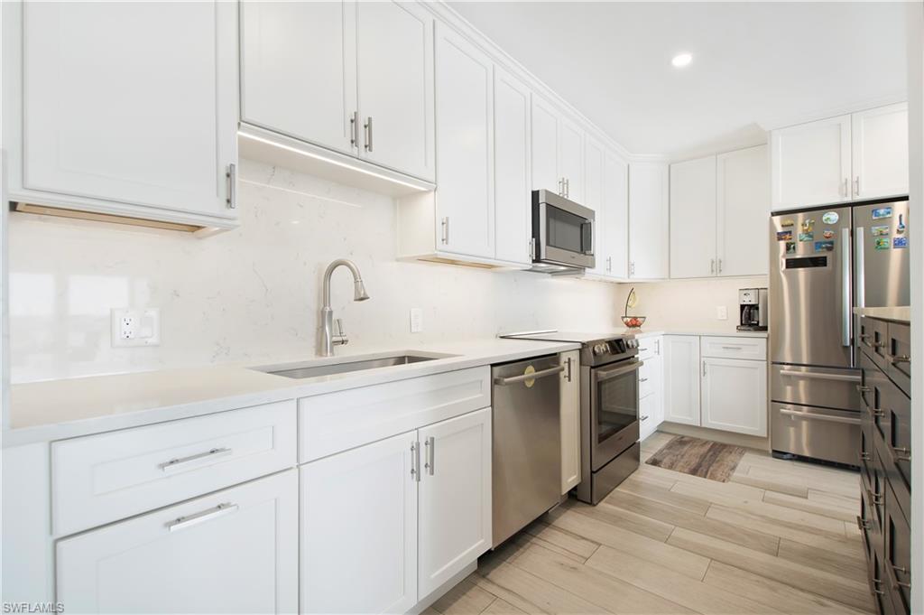 60 West Pelican Street, Unit 505 Naples, FL 34113 - Photo 8 of 41 a kitchen with white cabinets sink and stainless steel appliances