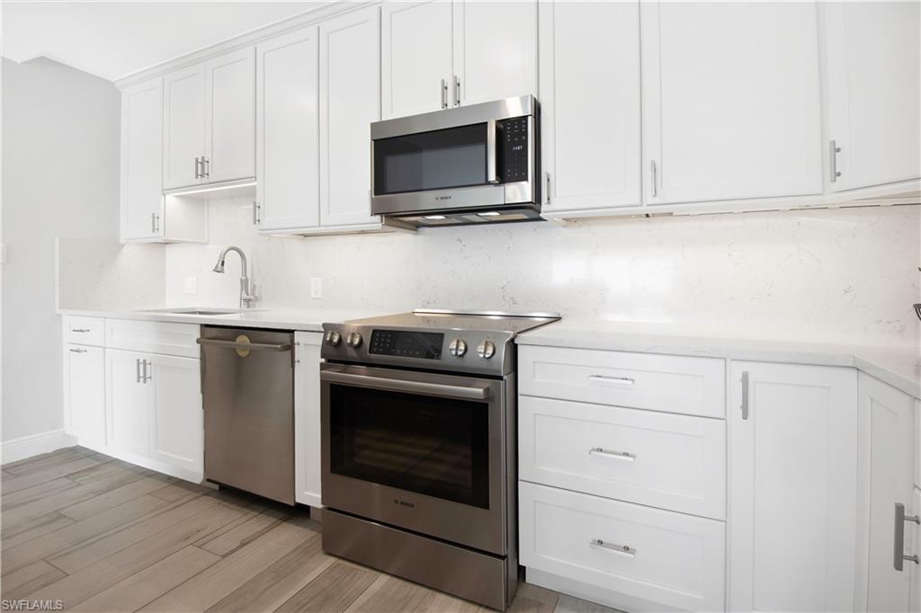 60 West Pelican Street, Unit 505 Naples, FL 34113 - Photo 9 of 41 a kitchen with stainless steel appliances granite countertop white cabinets a sink and dishwasher