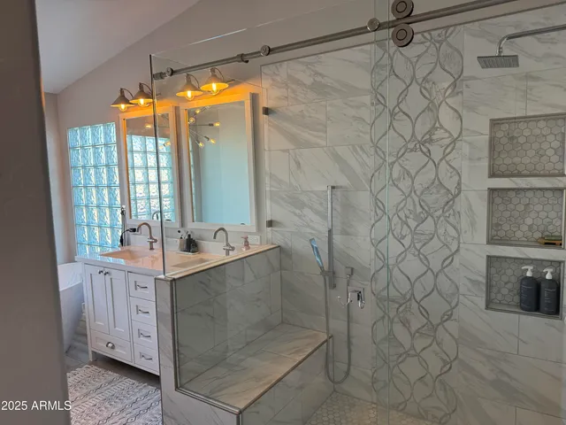a bathroom with a sink and mirror with shower