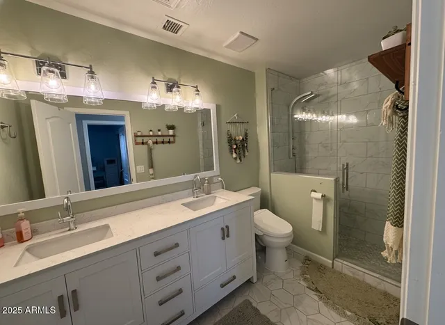 a bathroom with a double vanity sink toilet and shower