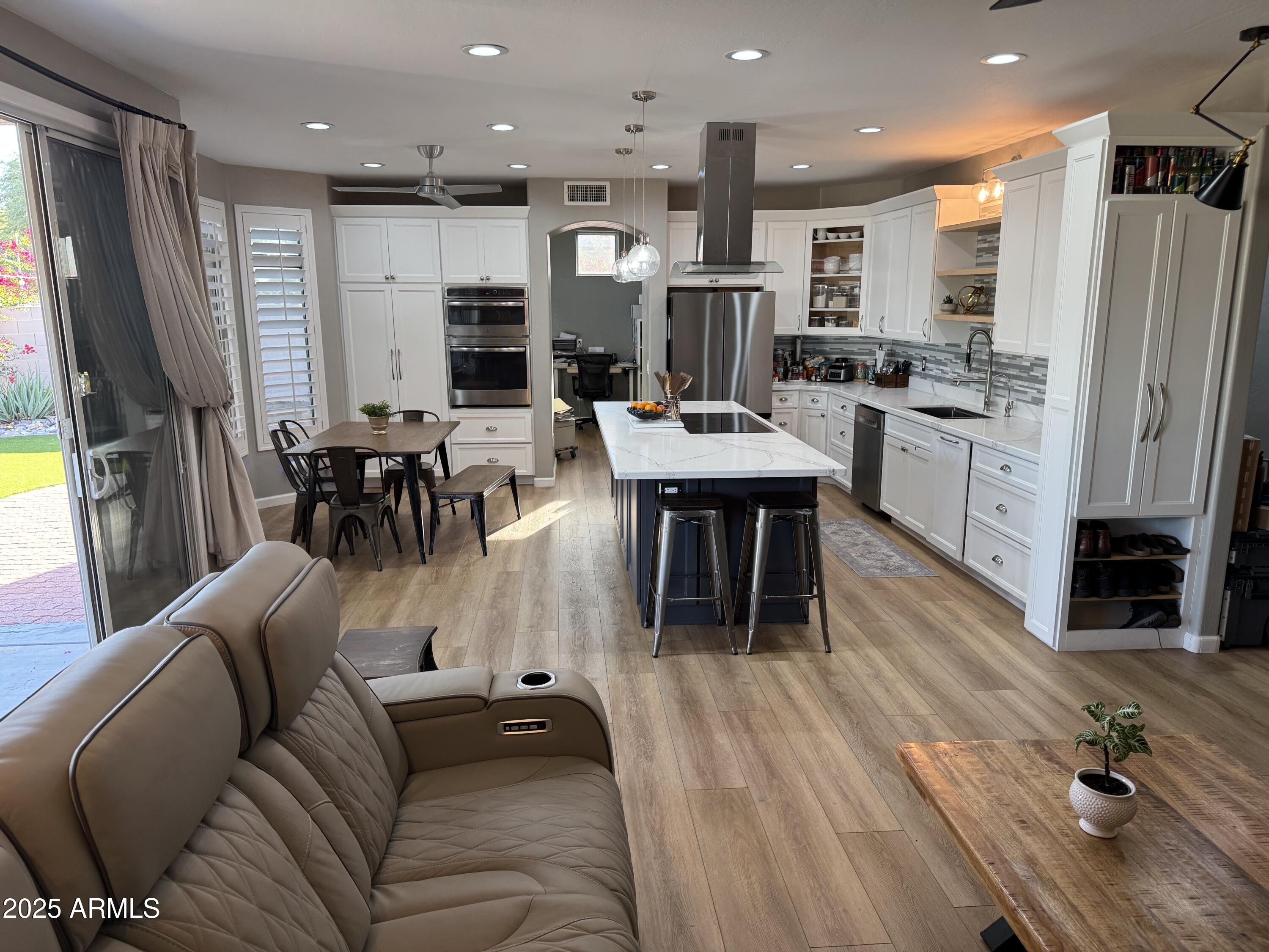 13781 West Vernon Avenue Goodyear, AZ 85395 - Photo 5 of 25 a living room with stainless steel appliances furniture wooden floor and a kitchen view