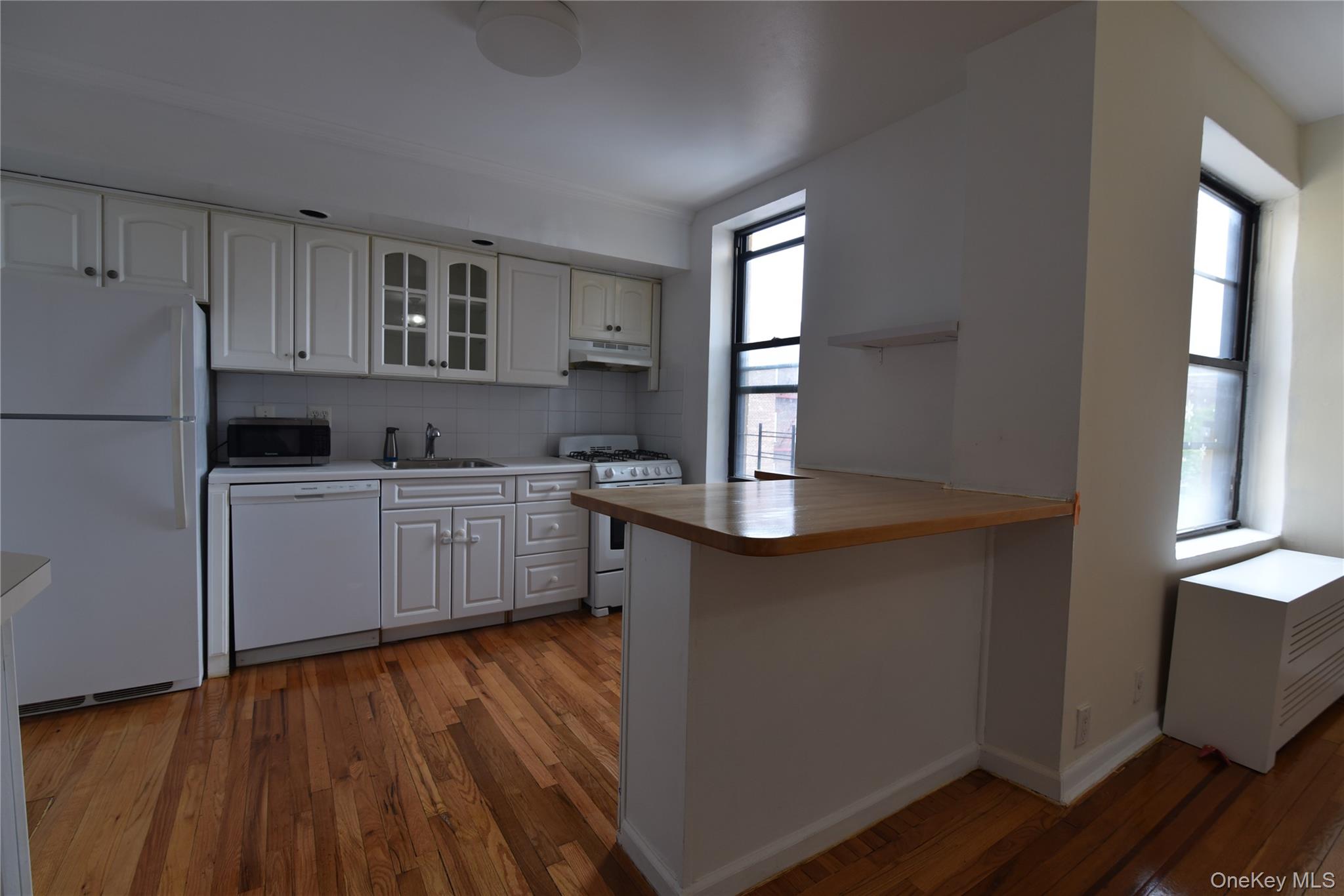 83-52 Talbot Street, Unit 5C Queens, NY 11415 - Photo 11 of 22 a kitchen with kitchen island granite countertop wooden floors and white cabinets