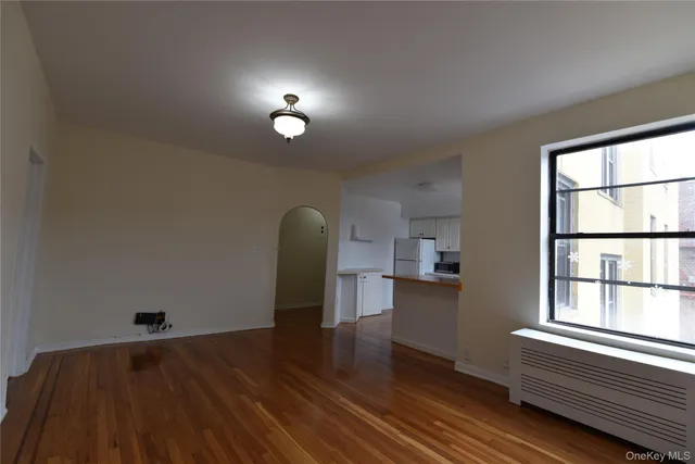 an empty room with wooden floor chandelier fan and windows