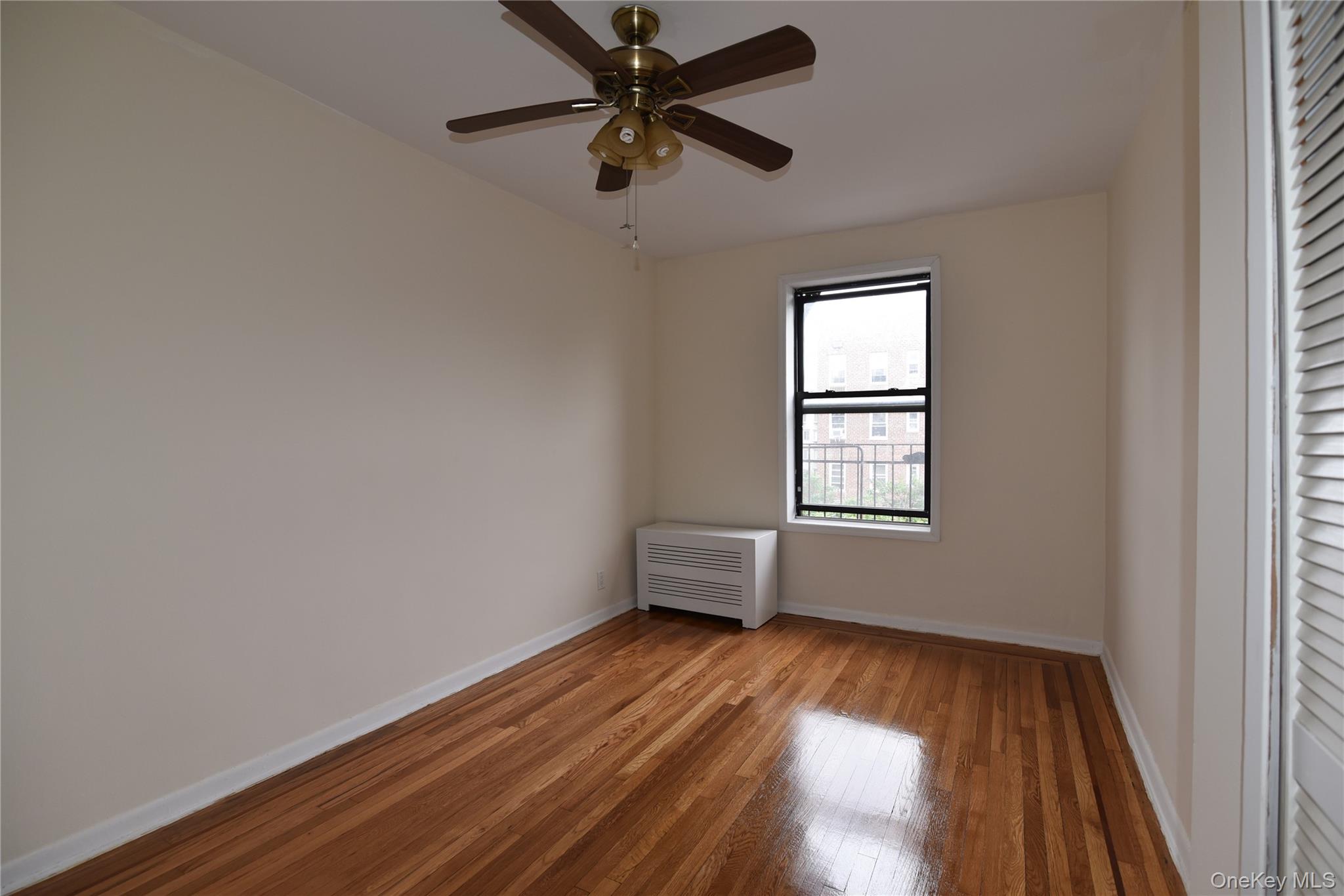 83-52 Talbot Street, Unit 5C Queens, NY 11415 - Photo 19 of 22 an empty room with wooden floor fan and windows
