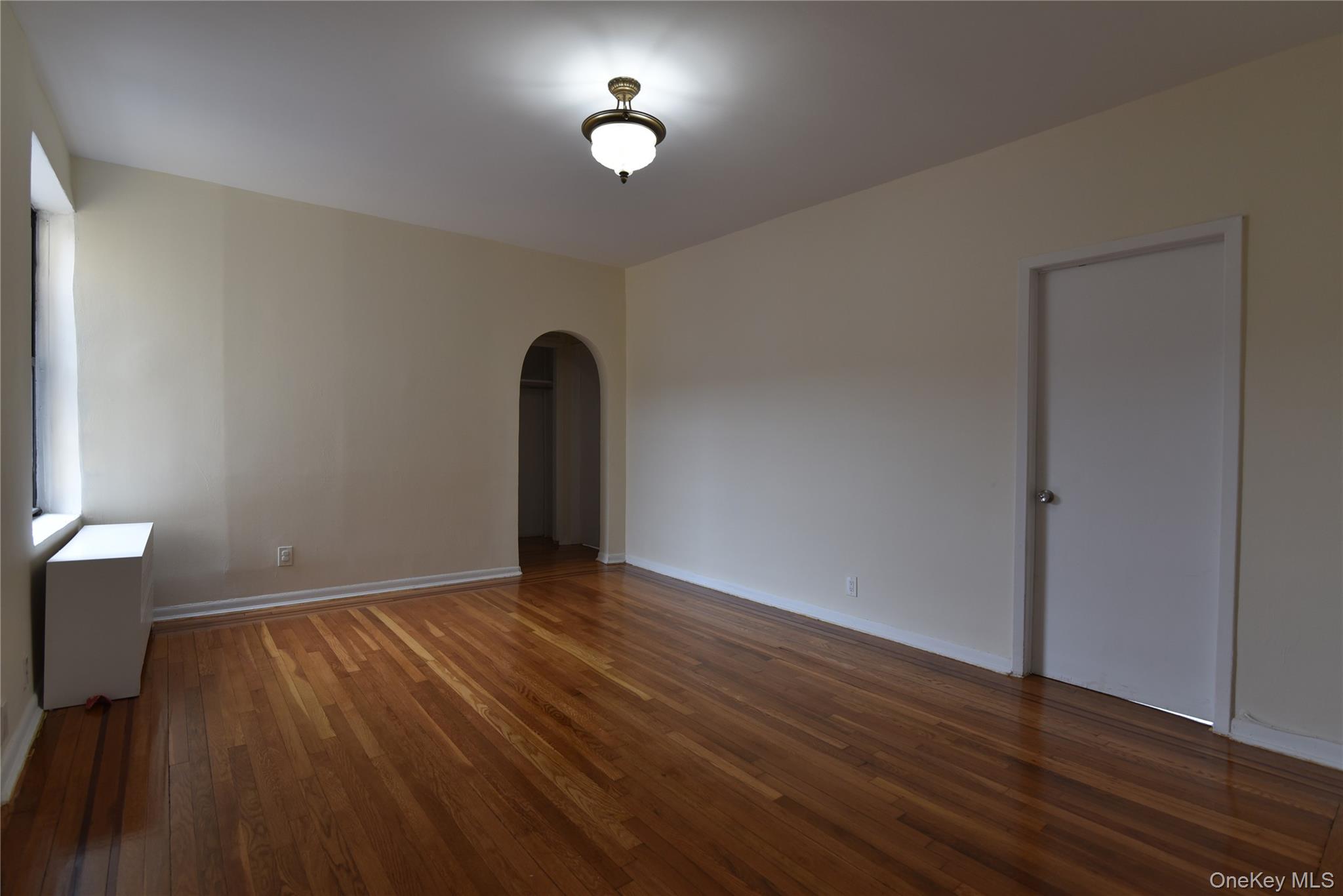 83-52 Talbot Street, Unit 5C Queens, NY 11415 - Photo 8 of 22 a view of an empty room with wooden floor and a window