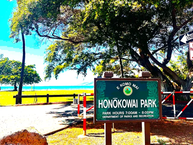 a sign that is sitting on a park next to a road