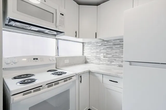 a kitchen with white cabinets and white appliances