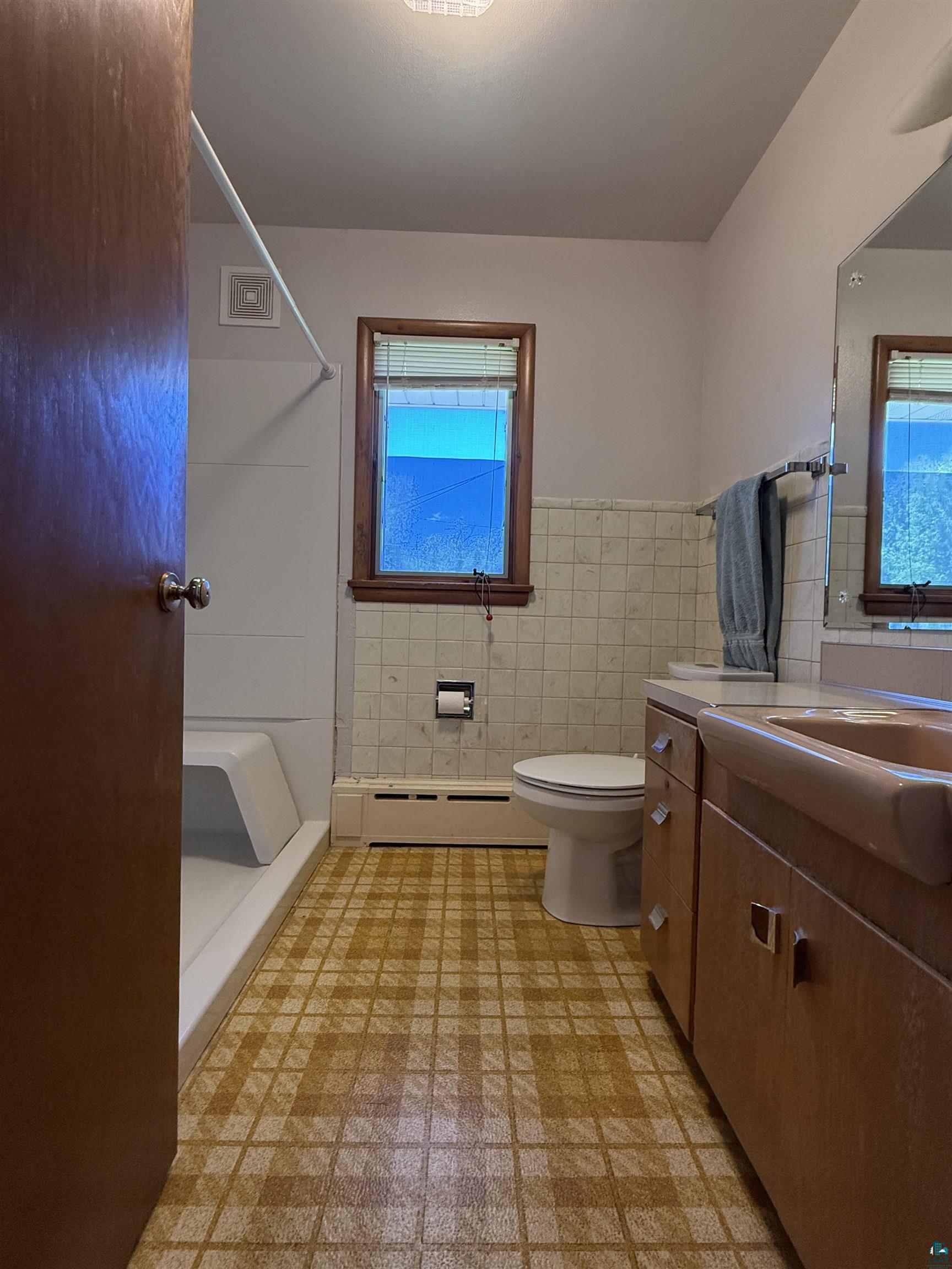 607 3rd Street Northeast Chisholm, MN 55719 - Photo 19 of 32 Bathroom featuring patterned vinyl flooring, a built-in vanity with integrated sink, and a window with wood trim