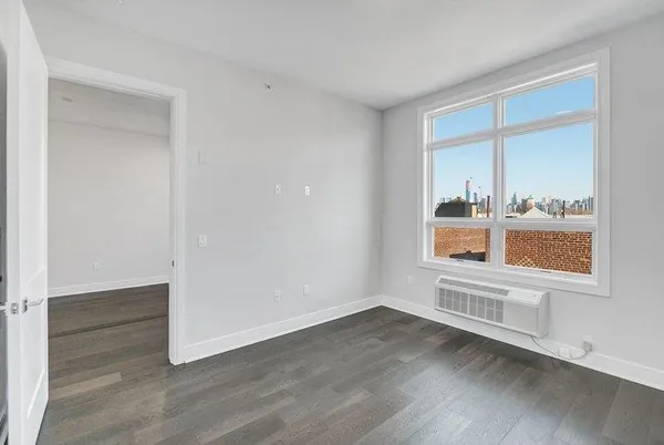 a view of an empty room with wooden floor and a window