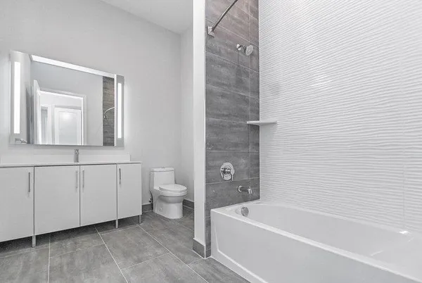 a bathroom with a white bath tub a mirror and a toilet