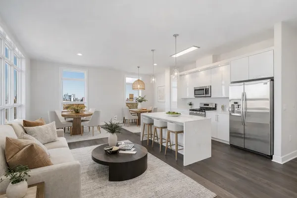a living room with stainless steel appliances kitchen island a table and chairs in it