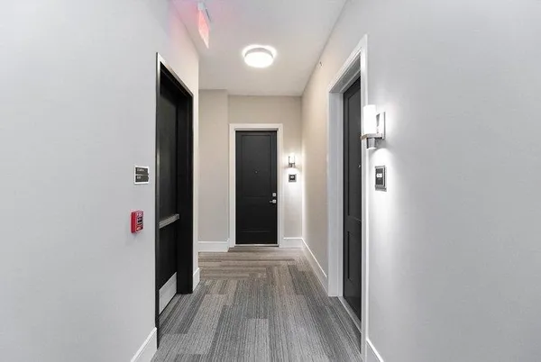 a view of a hallway with wooden floor and cabinets