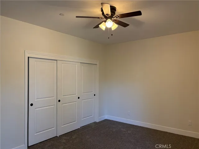 an empty room with a ceiling fan and window
