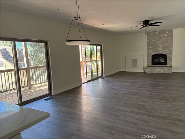 a view of an empty room with wooden floor fireplace and a window