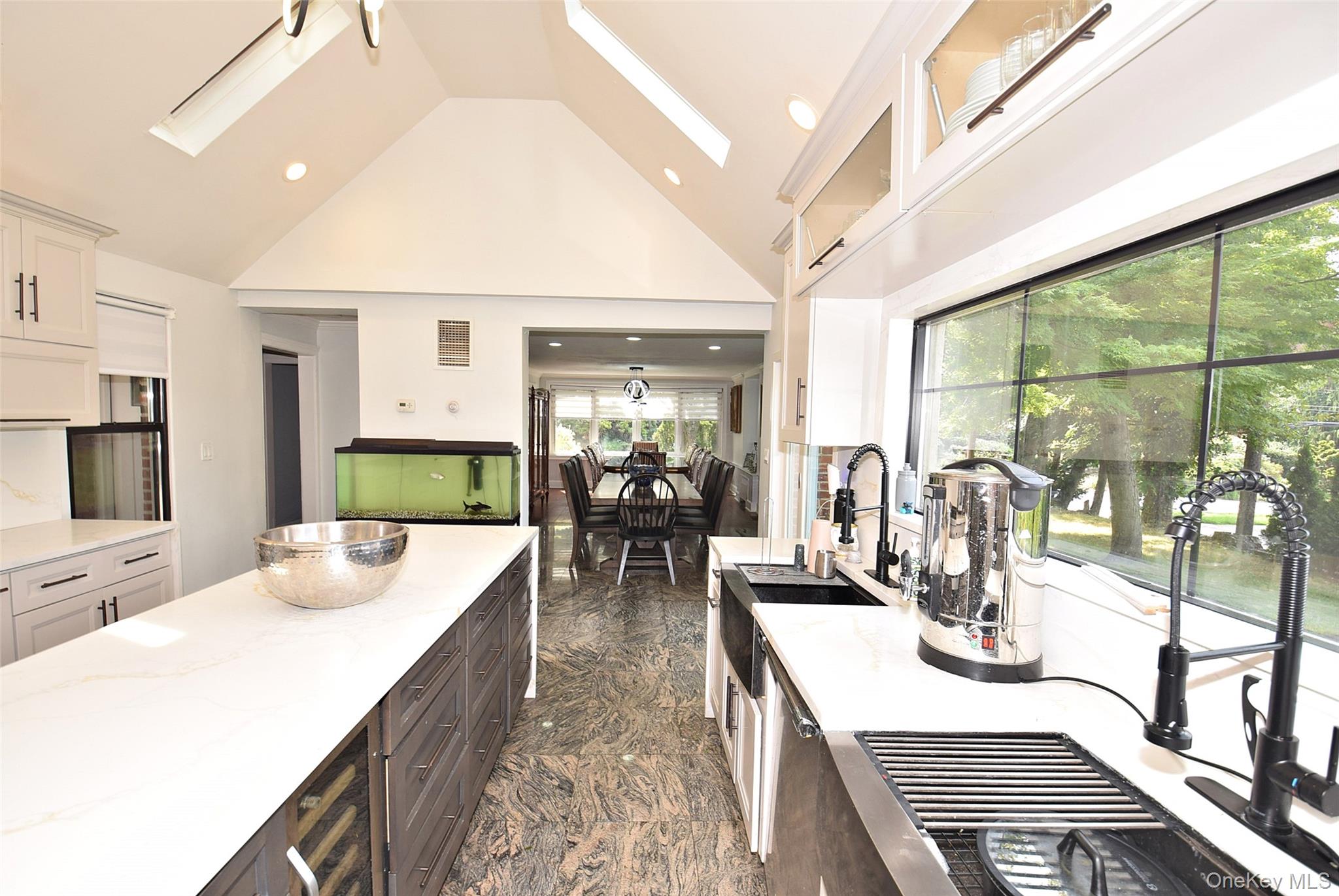 25 Old Mill Road Great Neck, NY 11023 - Photo 32 of 45 Vaulted ceiling with skylights, white cabinetry, integrated range hood, built-in wine refrigerator, and a large window above the kitchen 2 sinks.