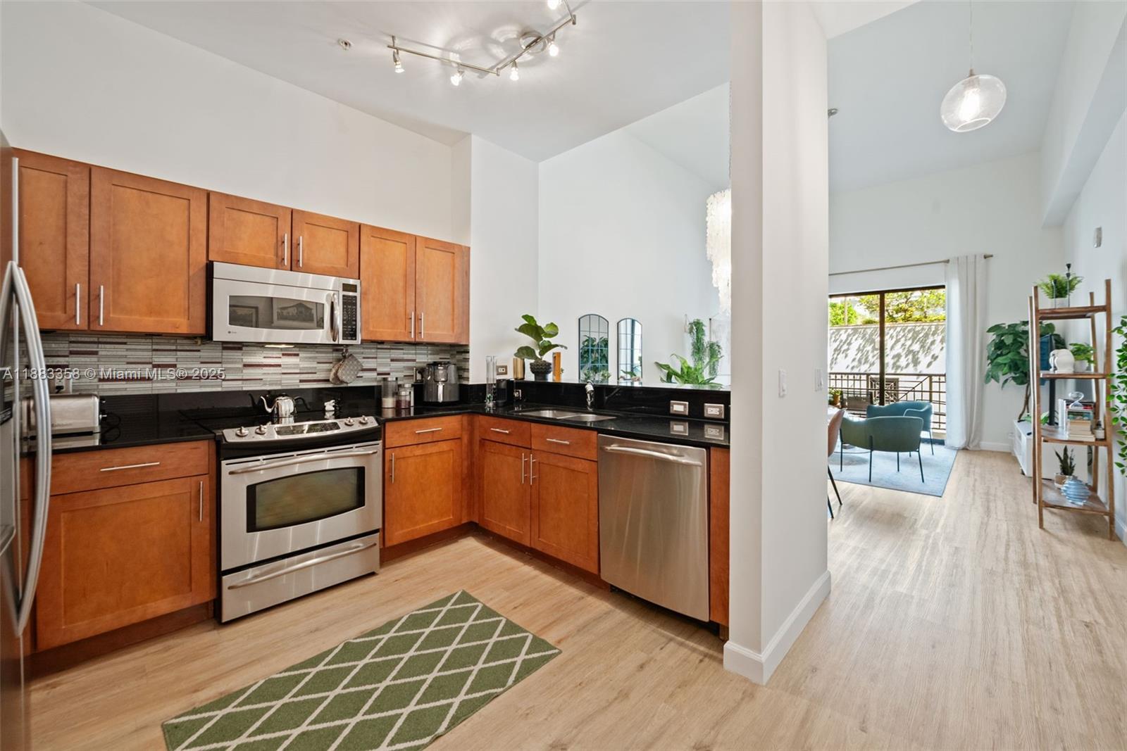 8390 Southwest 72nd Avenue, Unit 314 Miami, FL 33143 - Photo 7 of 35 a kitchen with stainless steel appliances granite countertop a stove top oven a sink dishwasher a dining table and chairs with wooden floor