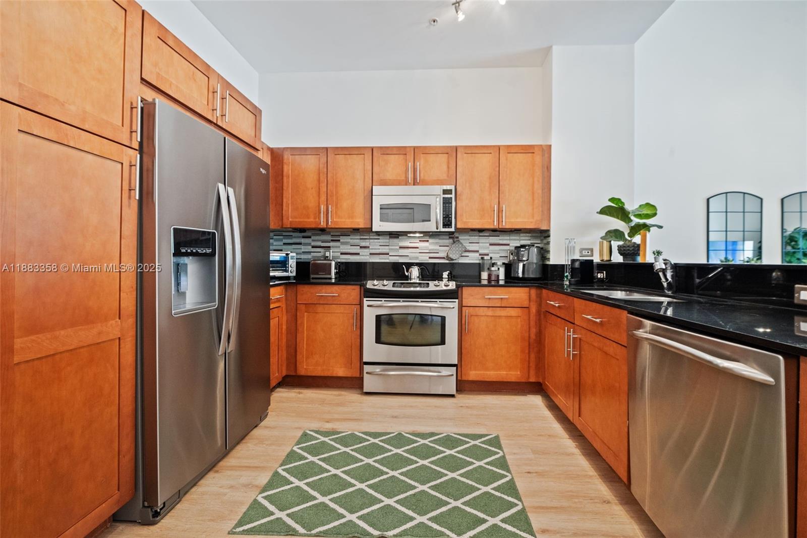 8390 Southwest 72nd Avenue, Unit 314 Miami, FL 33143 - Photo 8 of 35 a kitchen with stainless steel appliances granite countertop a stove a refrigerator and a sink